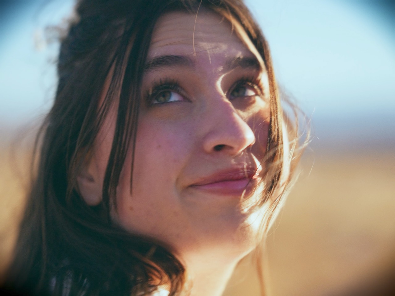 a young woman looks joyfully behind her in a bright field