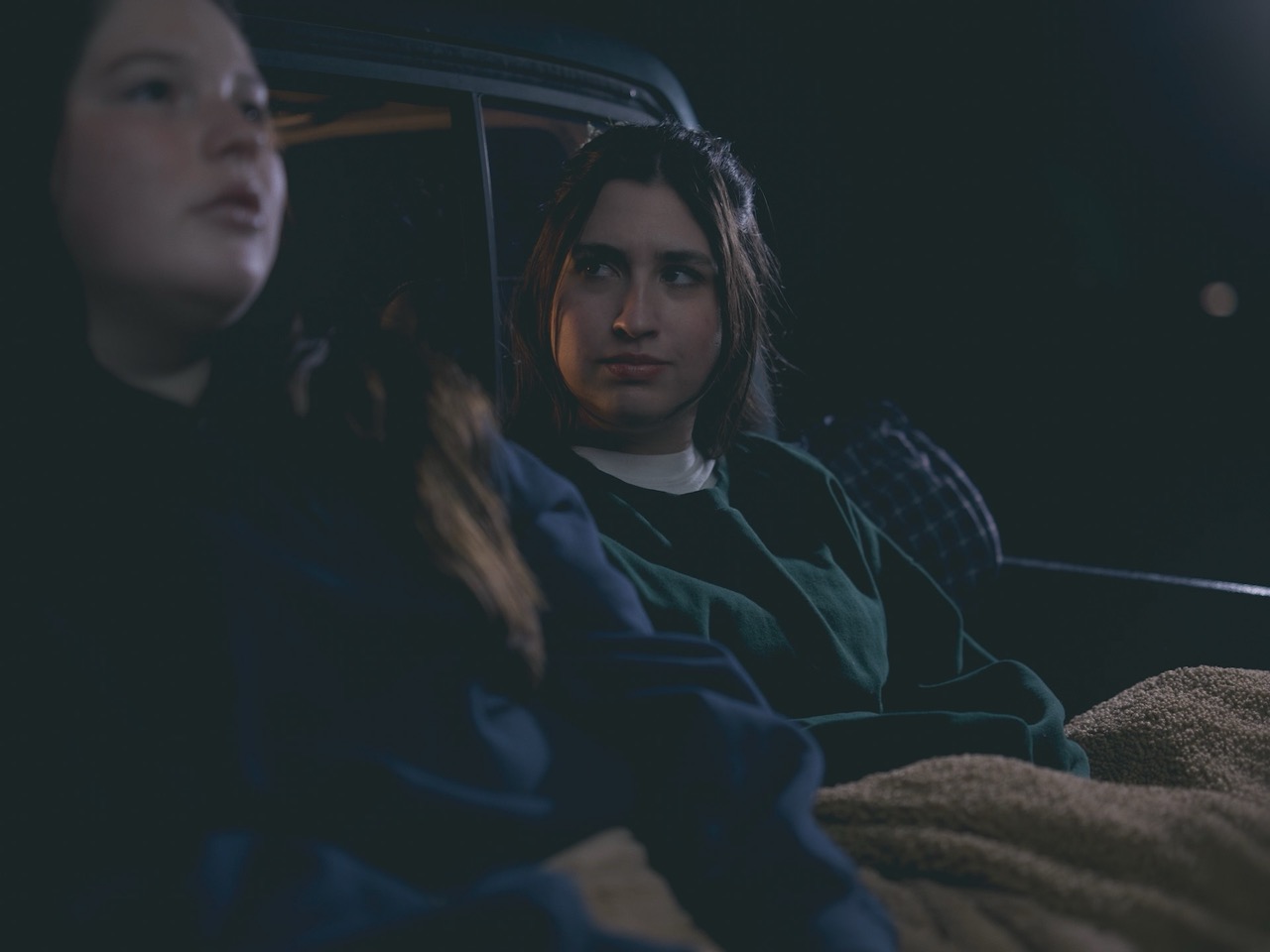 a woman looks longingly at another woman in the dark of night