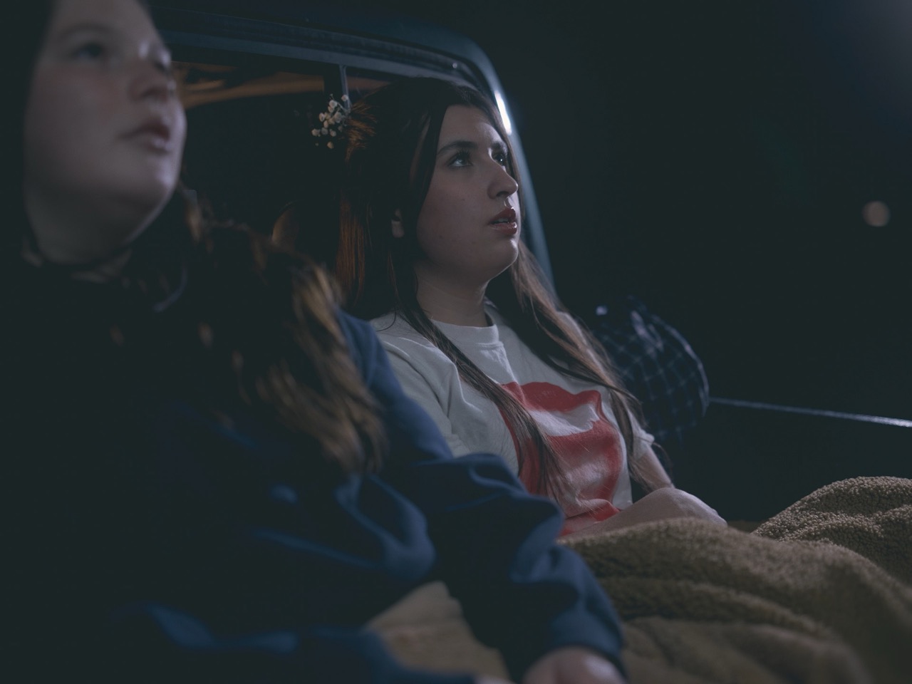 a woman looks off into the distance in the dark of night