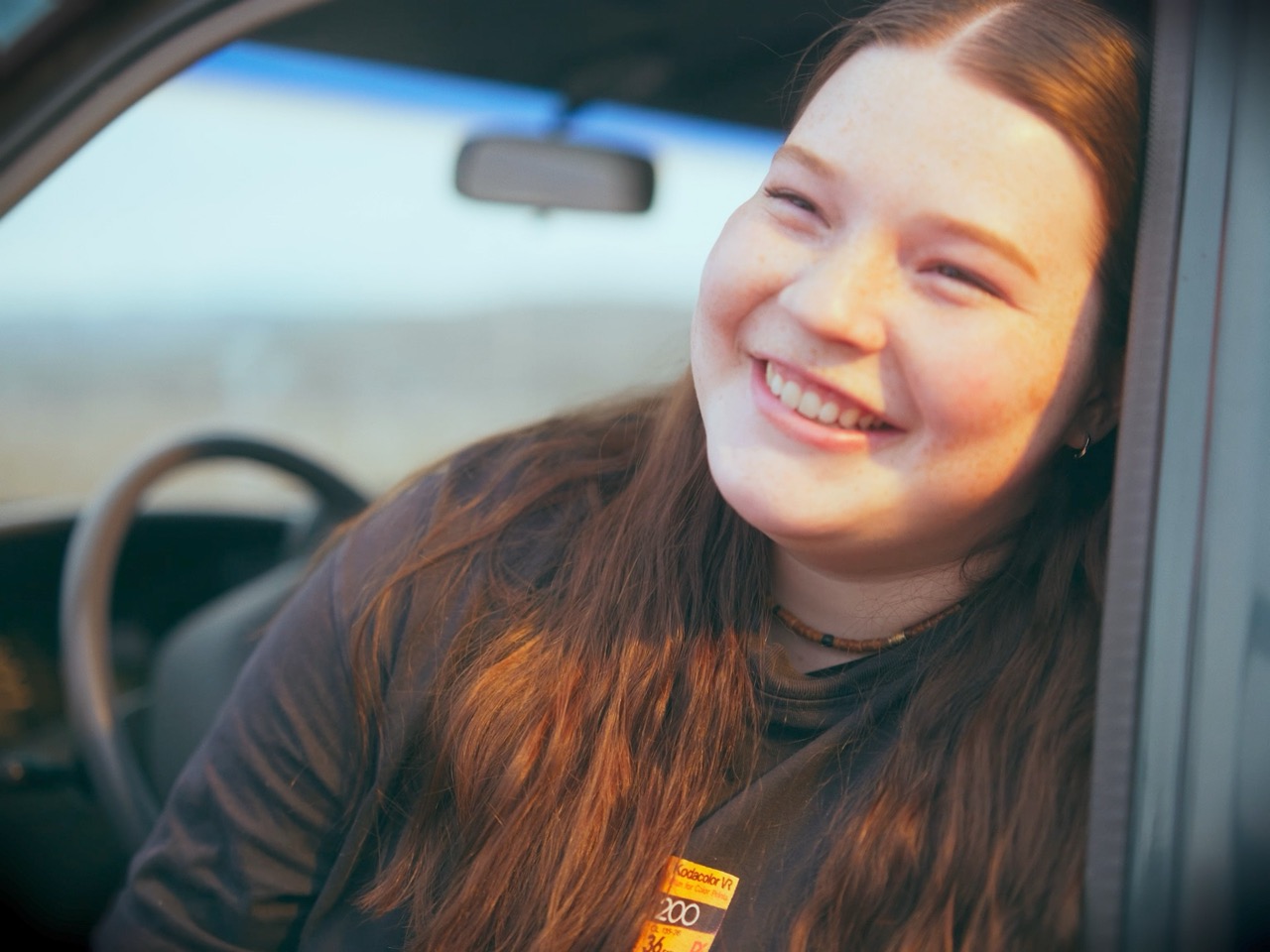 a young woman laughs from the cab of a truck