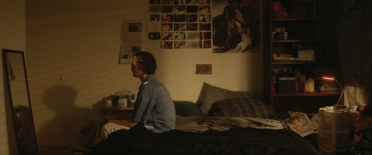 a man sits at the end of a bed in a dark room