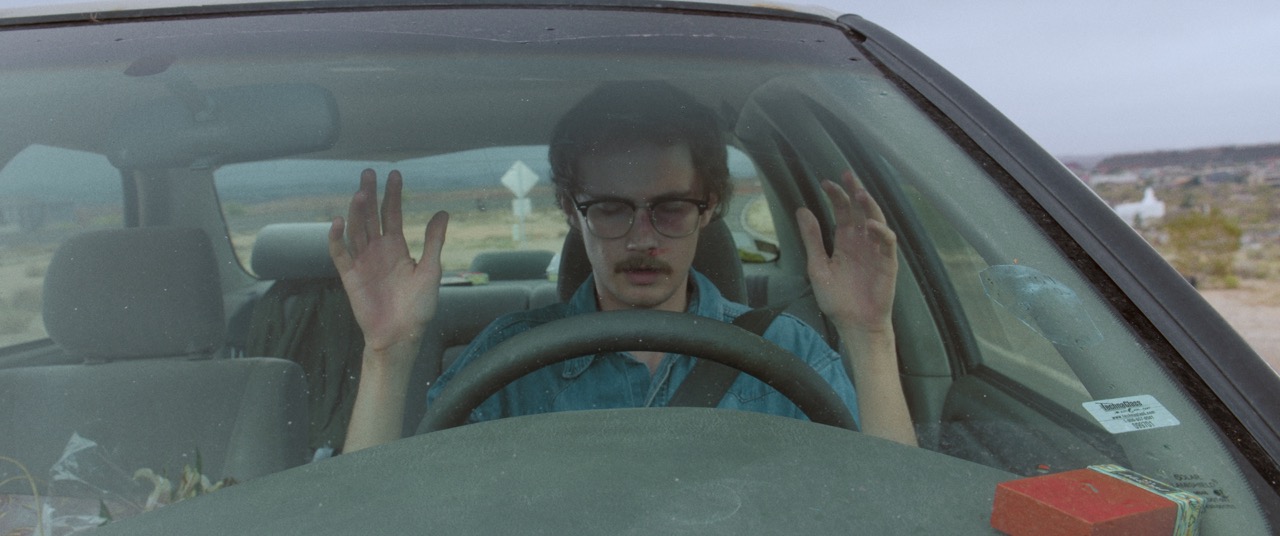 a man lifts his hands from the steering wheel in his car