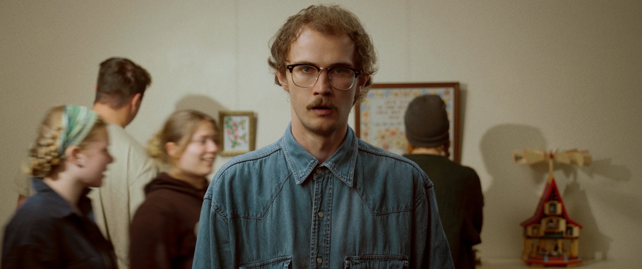 a man looks into the camera in a crowded room
