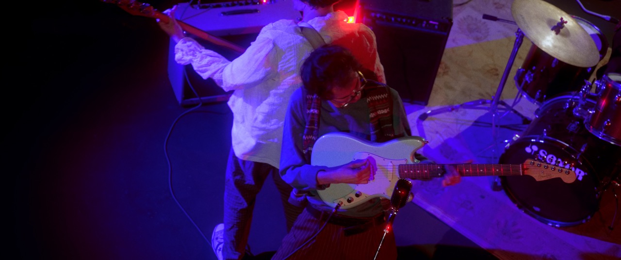two men play guitars in blue light