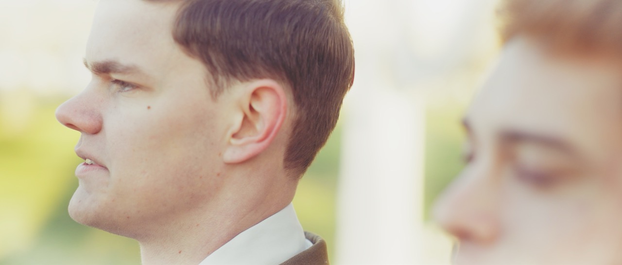 two men stand next to each other looking into the distance