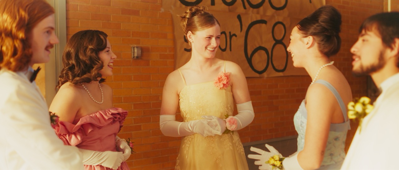 a woman in a prom dress is talking with a group of friends