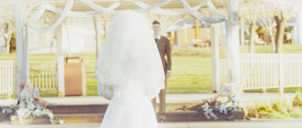 a woman in a wedding dress aproaches a man at the altar