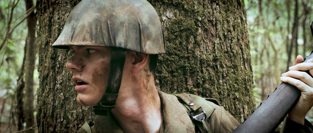 a man in a war uniform stands against a tree