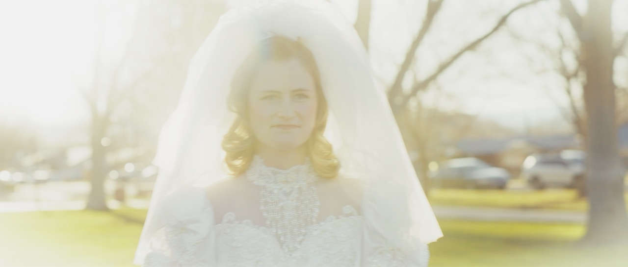 a woman in a white wedding dress walks through a field