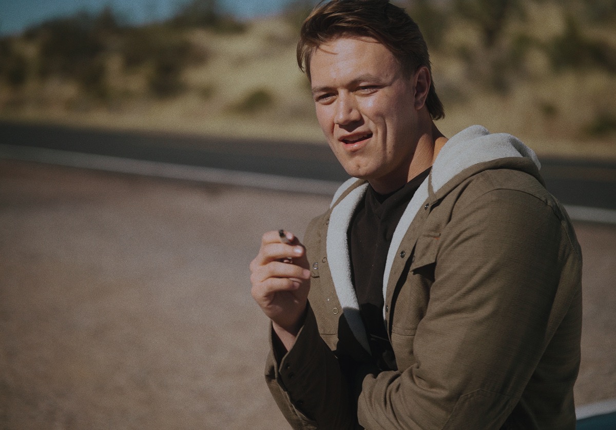 a boy stands with a cigarette in his hand