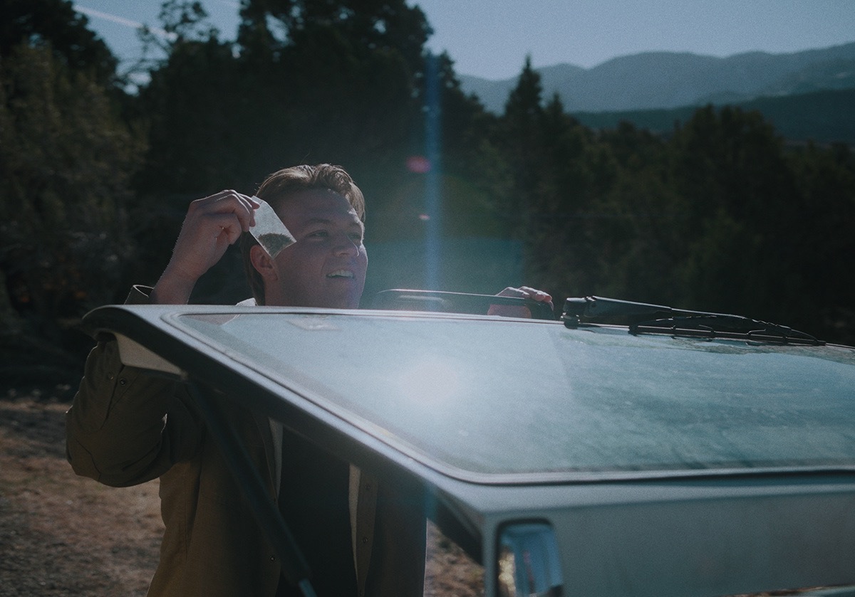 a boy holds something from the trunk of the station wagon