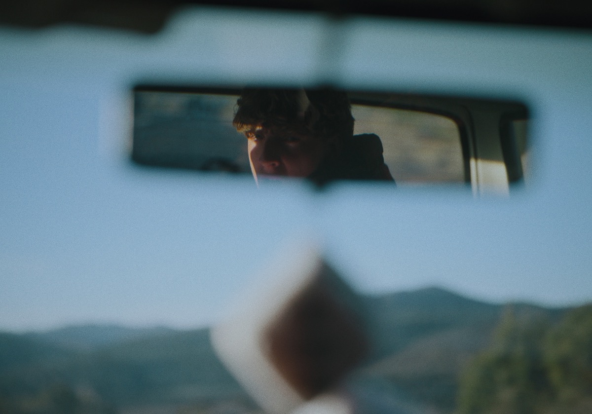 a boy is seen in the rear view mirror of a car