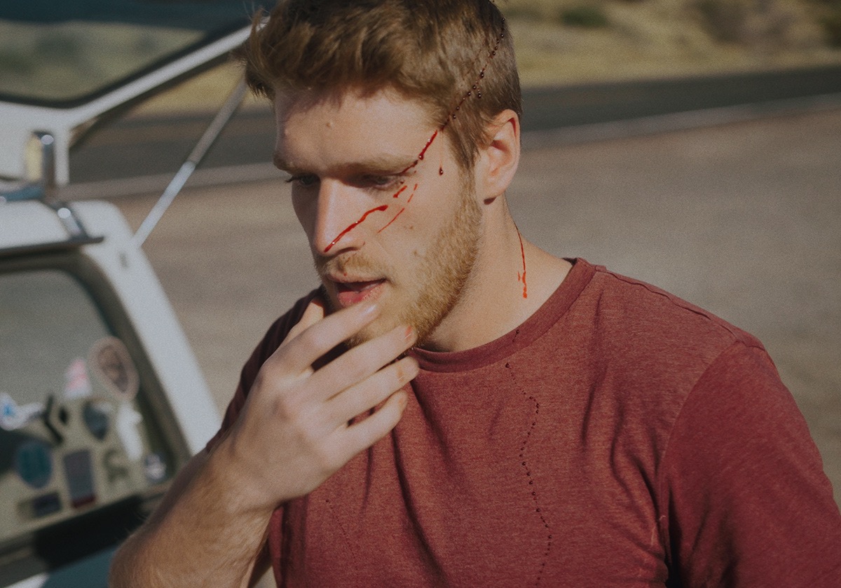 a boy looks in shock as he wipes blood off his face