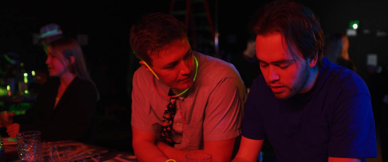 two men are in a dark room lit by red light