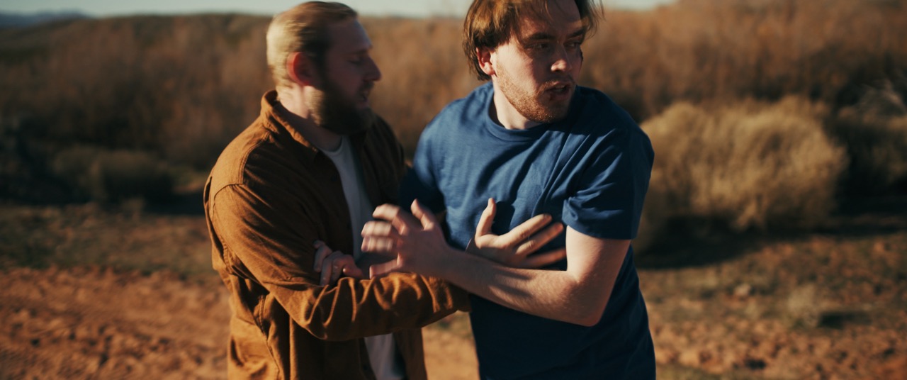 two men clutch each other in fear