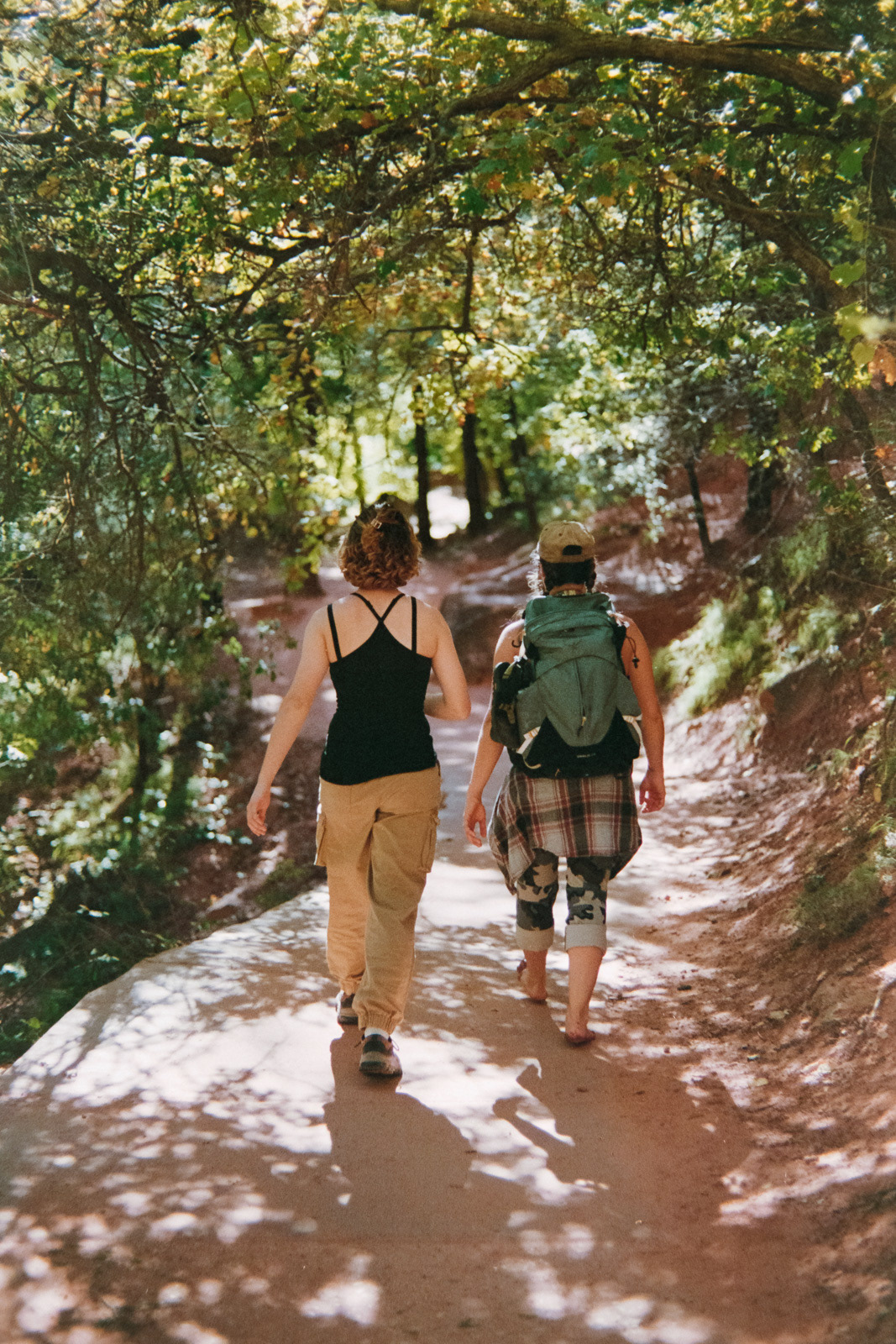 two girls walking through a tree covered walkway