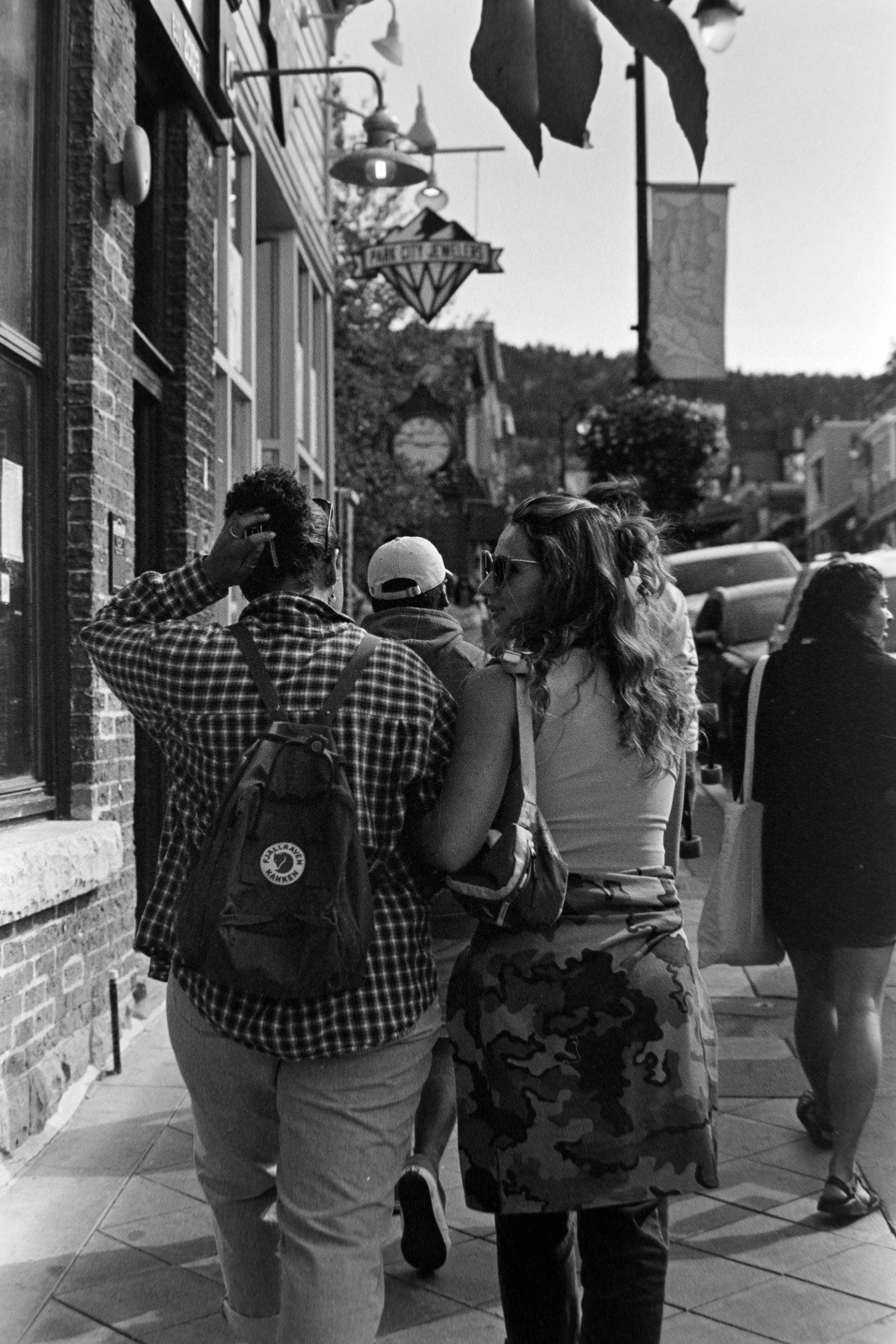 two girls wallk down a crowded street with arms locked