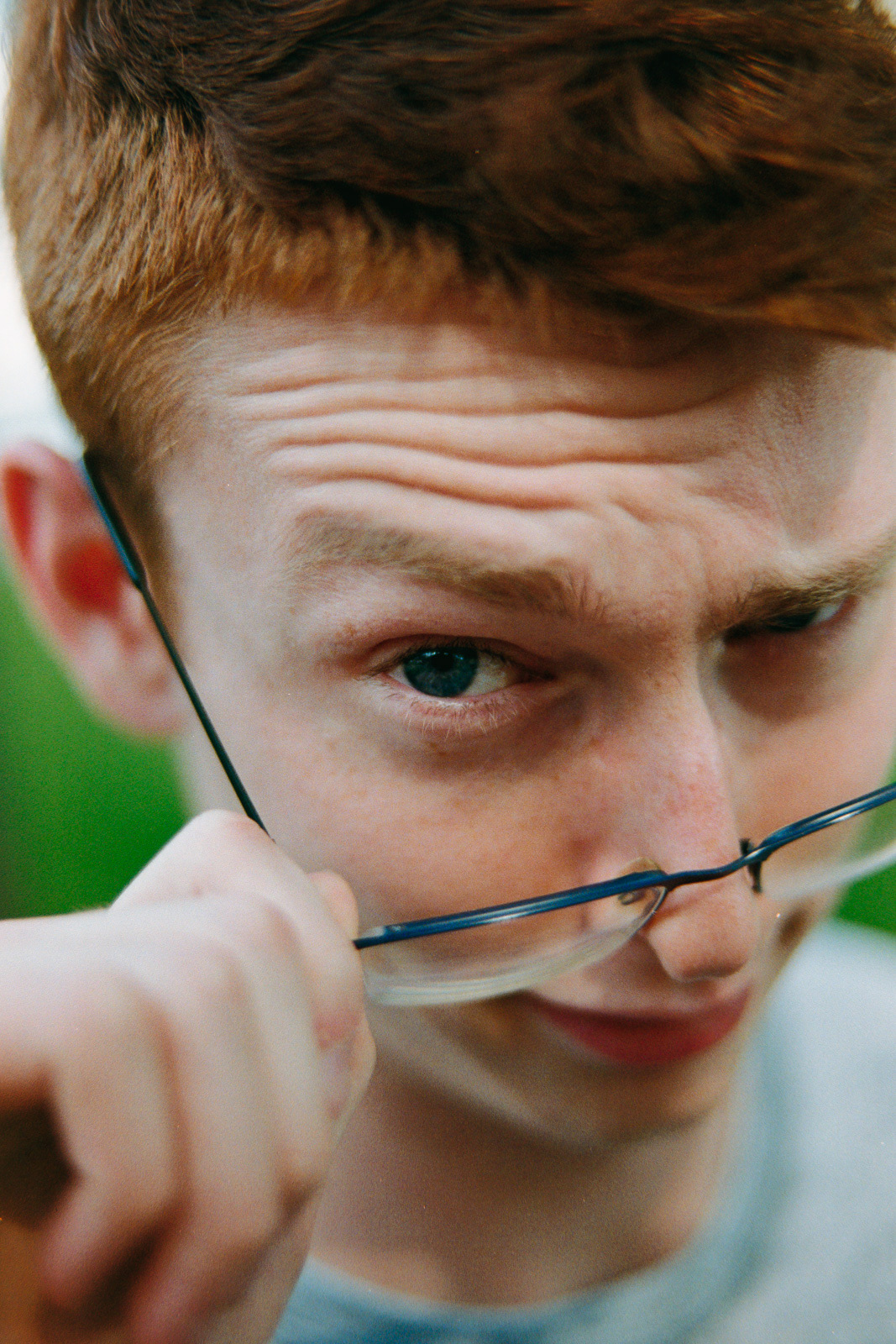 goofy portait of a boy looking into the camera over his glasses
