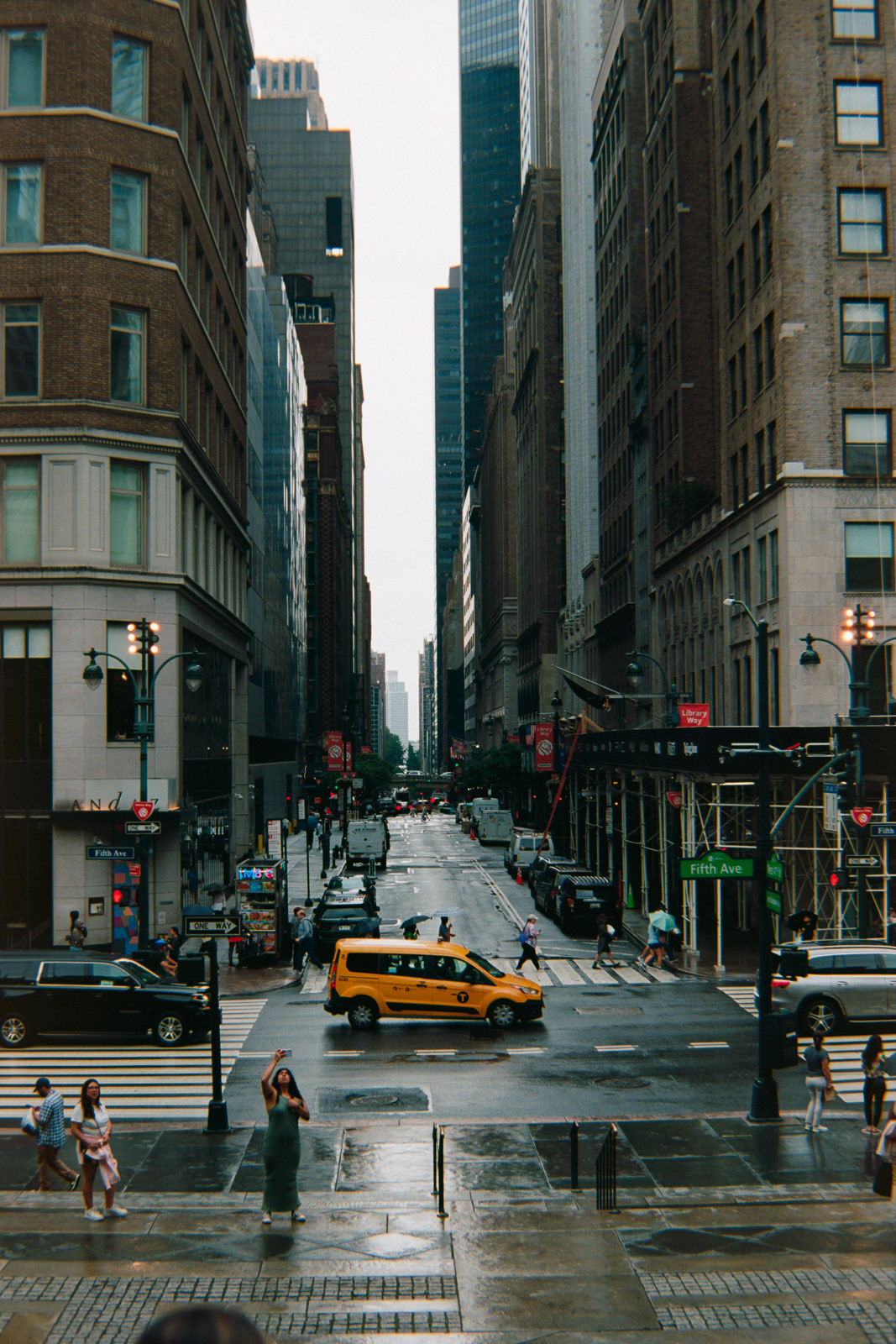 a yellow taxi appears small against the tall buildings of New York