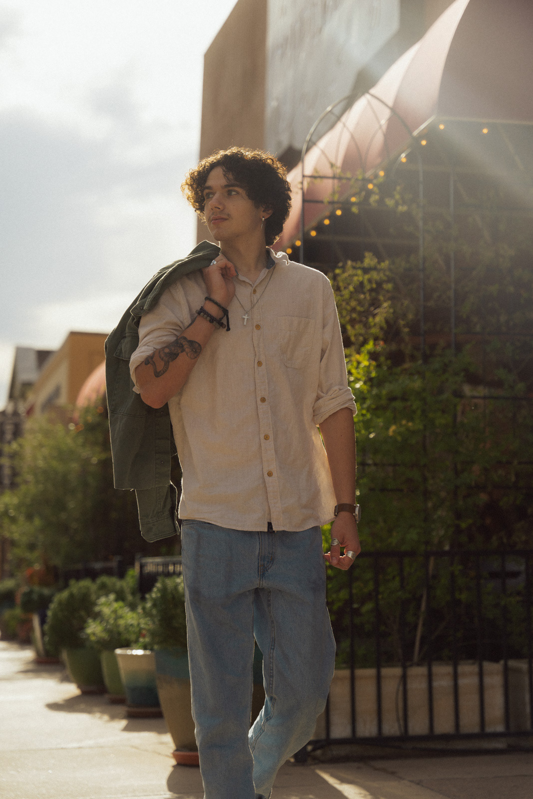 a man walks in front of shops as the sun glows behind him
