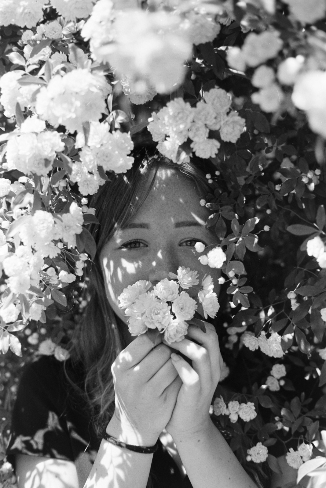 black and white portrait of a girl surrounded by bright flowers